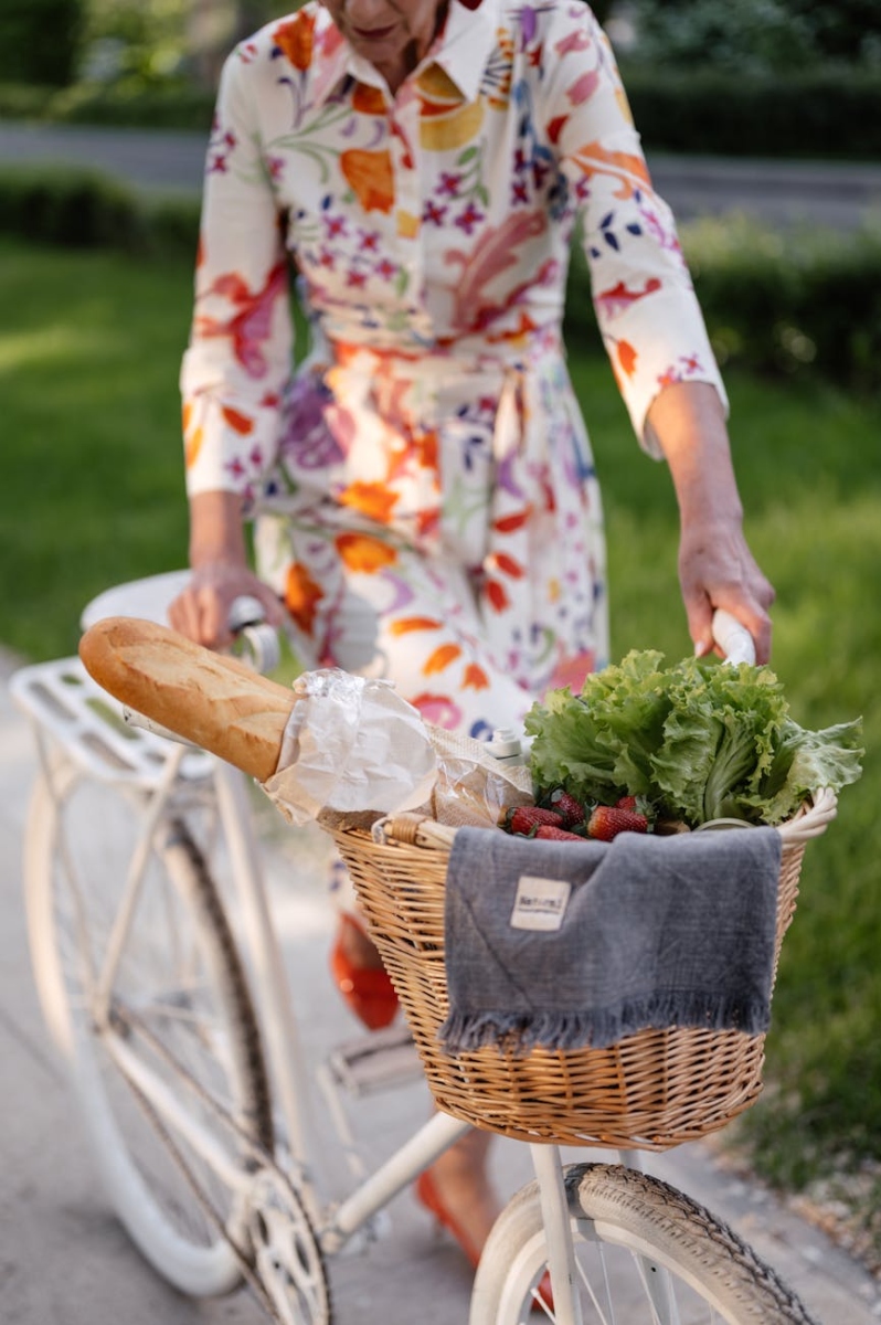 woman in floral dress holding a bicycle with brown wicker basket