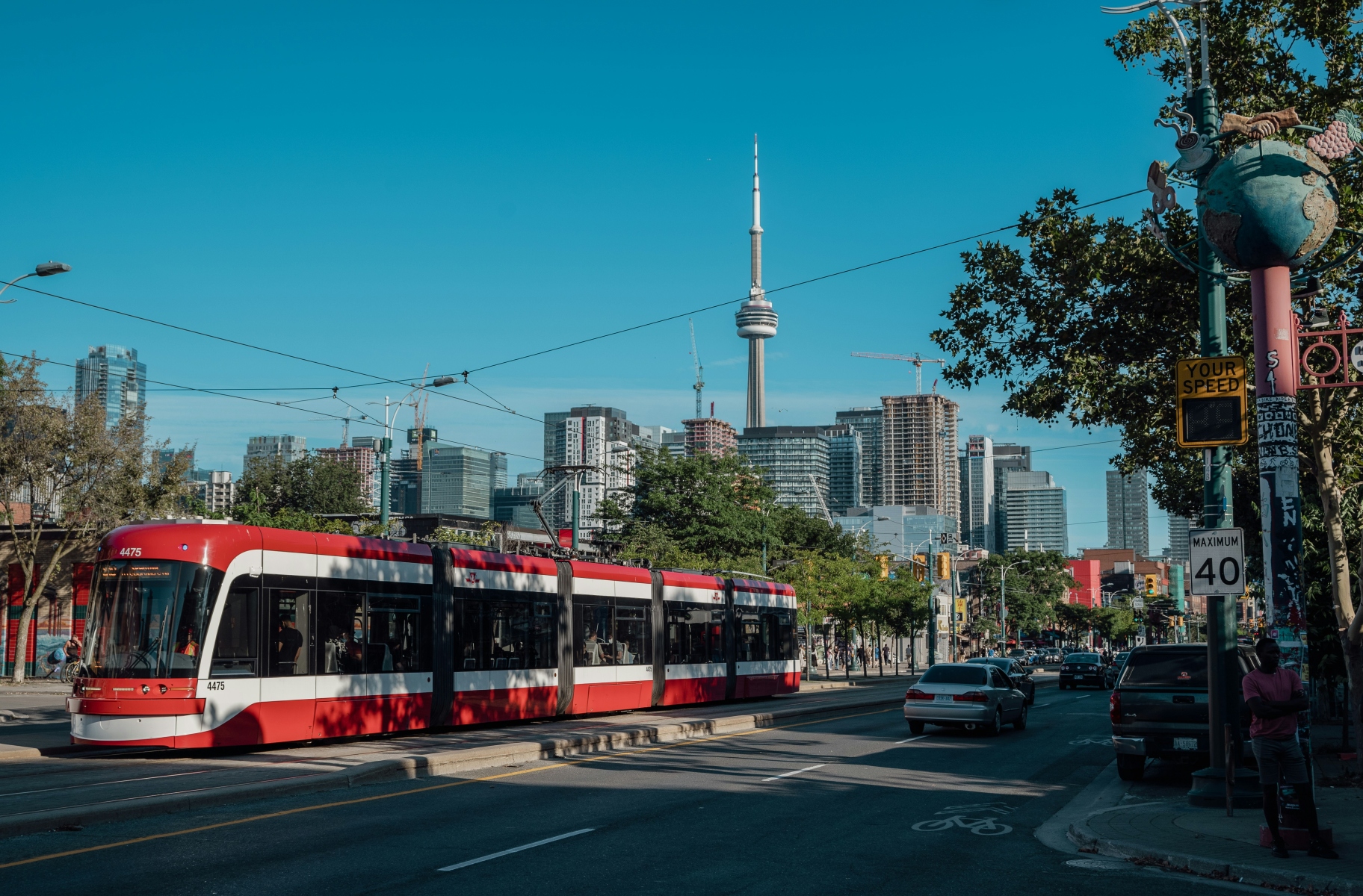 A red and white streetcar on a street with cars, buildings and the CN Tower in the background.